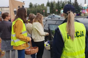 Uczestnicy Europejskiego Dnia Bez Ofiar Śmiertelnych stoją przy samochodzie zatrzymanego kierowcy