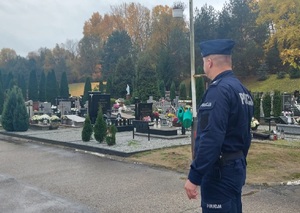 policjant obserwuje teren cmentarza
